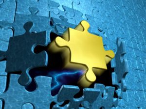 Golden puzzle piece bursting out of blue puzzle pieces